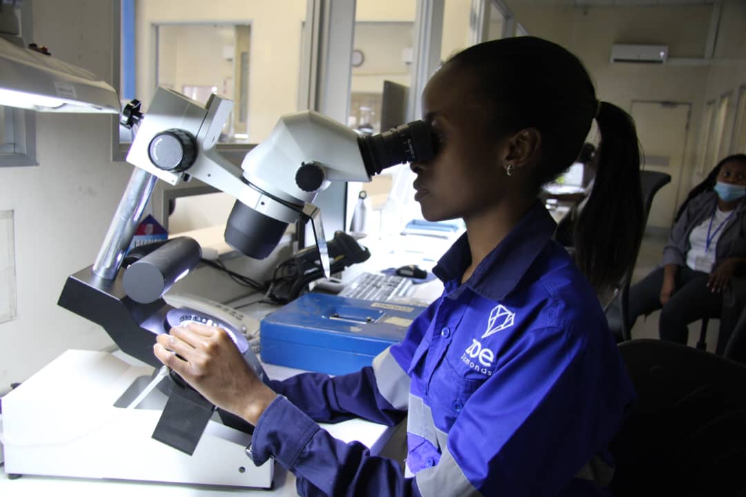 A woman examining diamonds under a microscope